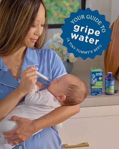 A bottle of gripe water with a dosing syringe beside a swaddled baby